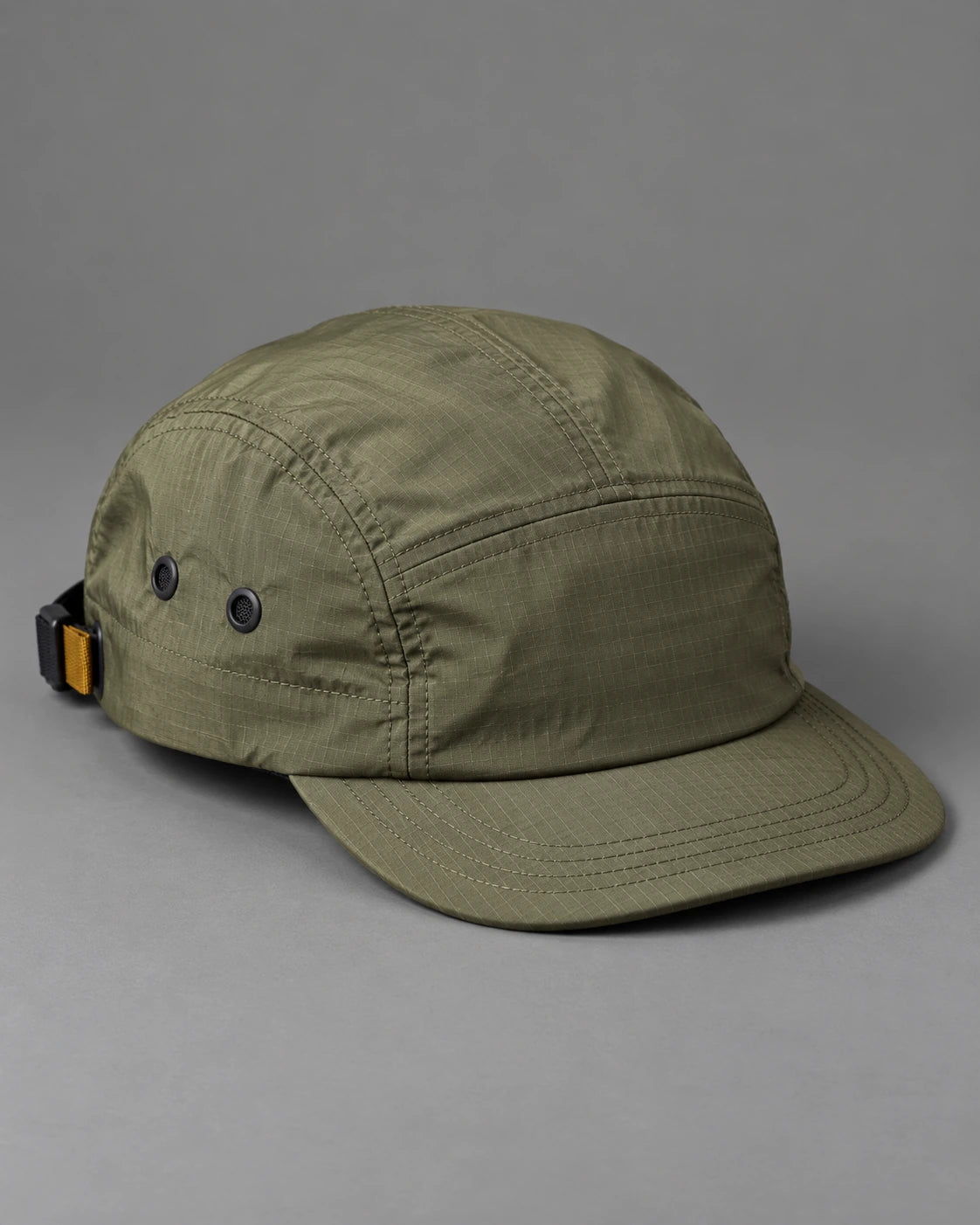 Olive five-panel outdoor cap with a short curved brim on a neutral grey studio background.