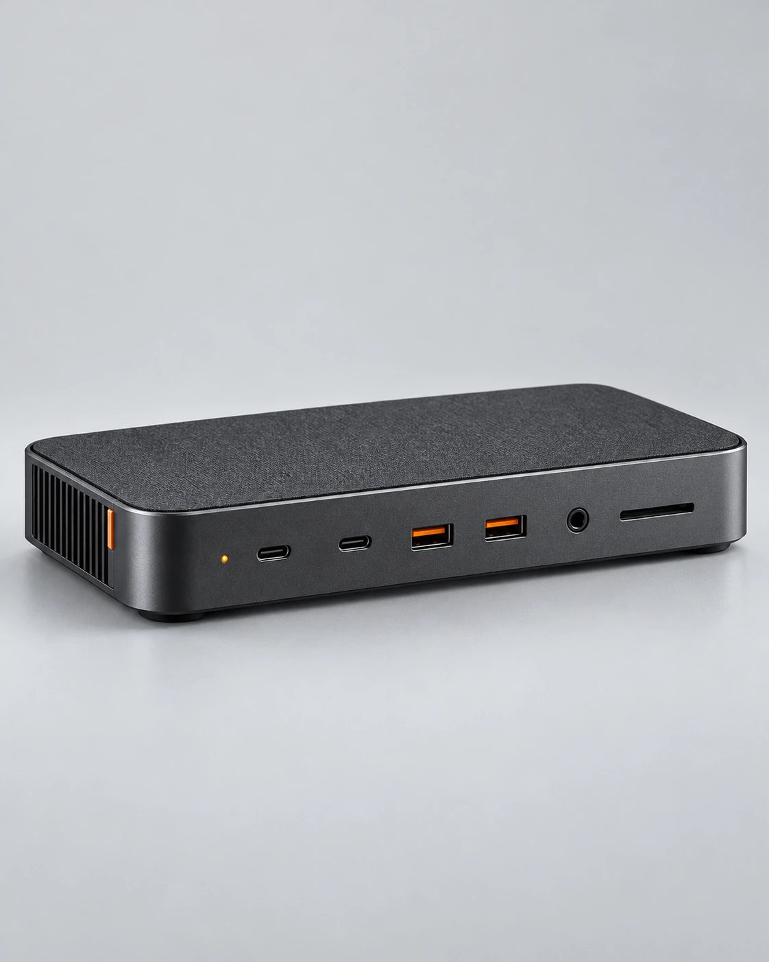 Dark aluminium desktop dock with visible front ports and a small orange detail on a cool-grey background.